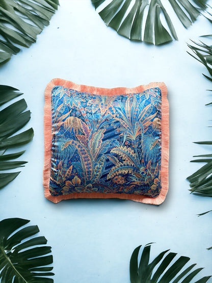 Close-up image of a Liberty Fabric Adelphi Voyage Silk Cushion with a peach fringe edge. The cushion features intricate patterns on luxurious silk fabric, adding a touch of elegance and sophistication to any home decor.