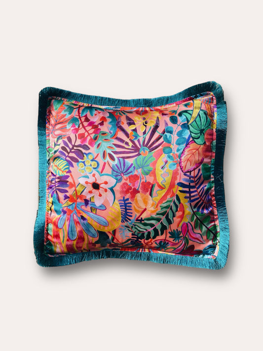 Close-up image of a Liberty Fabric Jungle Trip Silk Cushion with a teal green fringe edge. The cushion features intricate jungle-inspired patterns on luxurious silk fabric, adding vibrancy and sophistication to any home decor.