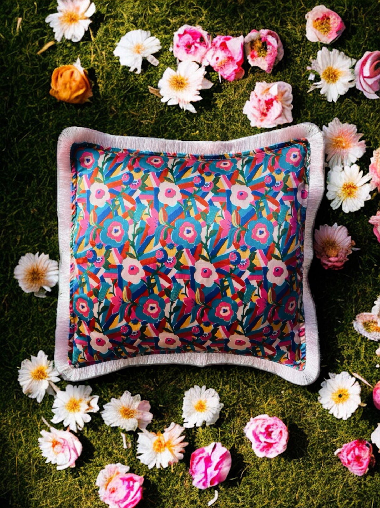 Close-up image of a Liberty Fabric Bloomsbury Silk Cushion with a powder pink fringe edge. The cushion features intricate patterns inspired by the Bloomsbury design on luxurious silk fabric, adding elegance and charm to any home decor.