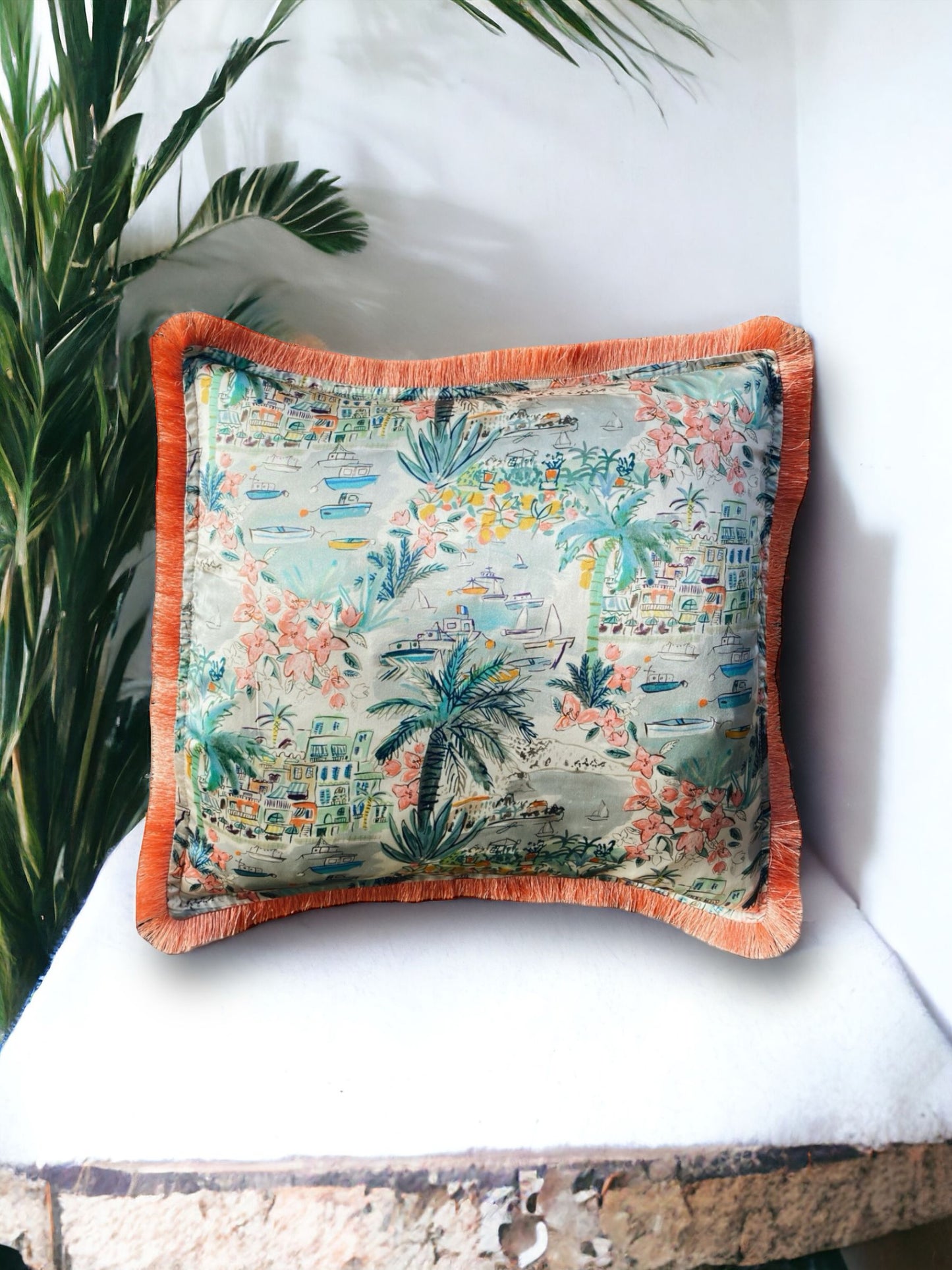 Close-up image of a Liberty Fabric Cape Vista Silk Cushion with a coral orange fringe edge. The cushion showcases intricate patterns on luxurious silk fabric, adding vibrancy and elegance to any home decor.