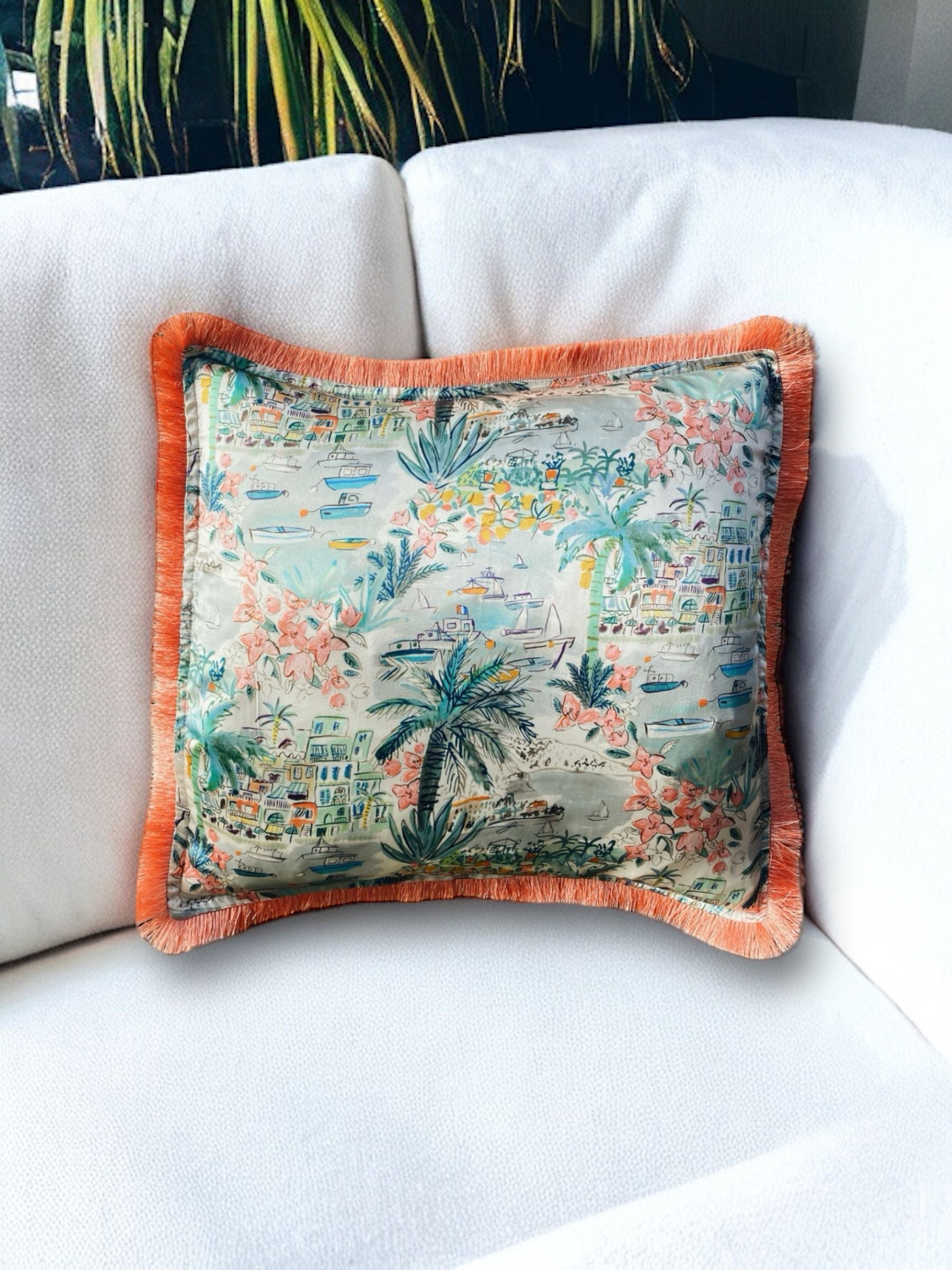 Close-up image of a Liberty Fabric Cape Vista Silk Cushion with a coral orange fringe edge. The cushion showcases intricate patterns on luxurious silk fabric, adding vibrancy and elegance to any home decor.