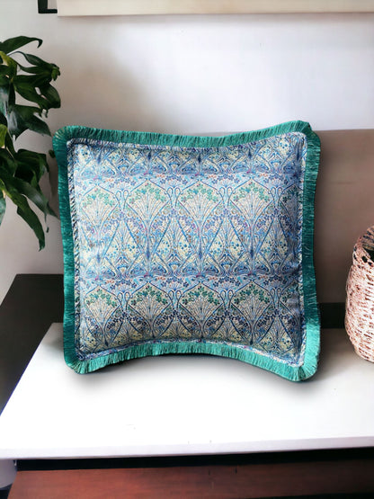 Close-up image of a Liberty Fabric Ianthe Blossom Silk Cushion with a pine green fringe edge. The cushion showcases intricate floral patterns inspired by Ianthe Blossom design on luxurious silk fabric, adding elegance and charm to any home decor.