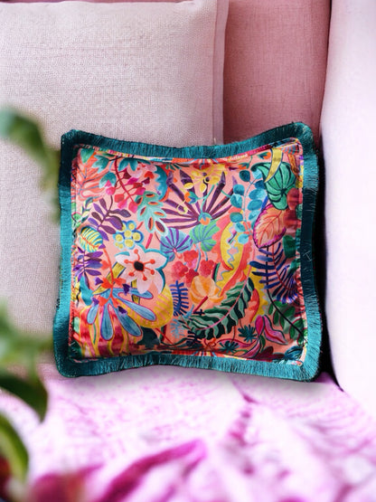 Close-up image of a Liberty Fabric Jungle Trip Silk Cushion with a teal green fringe edge. The cushion features intricate jungle-inspired patterns on luxurious silk fabric, adding vibrancy and sophistication to any home decor.