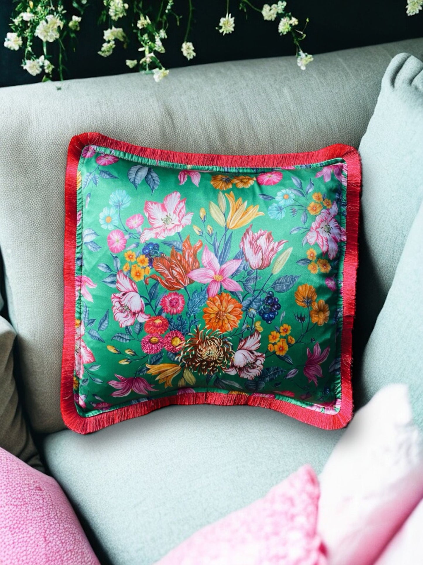 Close-up image of a Liberty Fabric Stately Bouquet Silk Cushion with a fuchsia pink fringe edge. The cushion features intricate floral patterns on luxurious silk fabric, adding vibrancy and elegance to any home decor.