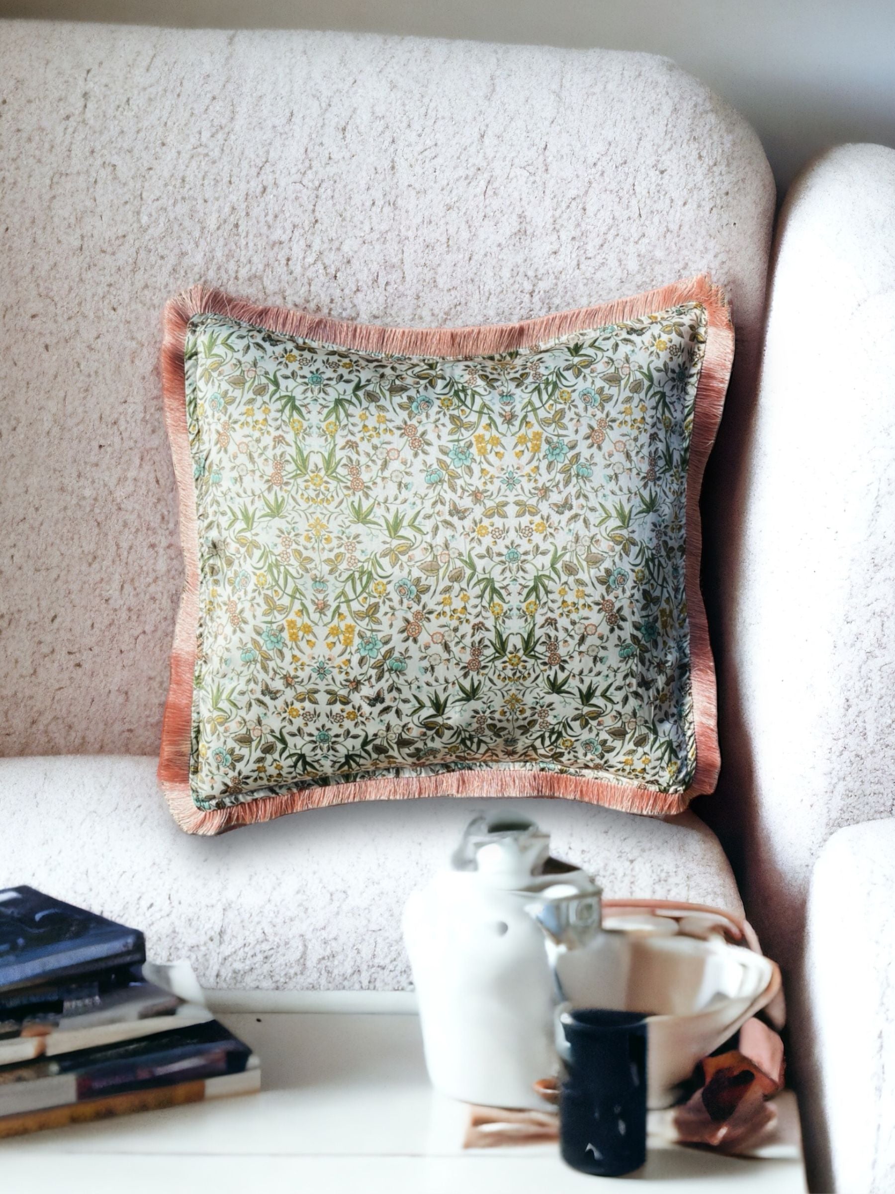 Close-up image of a Liberty Fabric Tapestry Silk Cushion with a delicate dusty pink fringe edge. The cushion features an intricate tapestry design crafted from sumptuous silk, adding sophistication and warmth to any home decor.